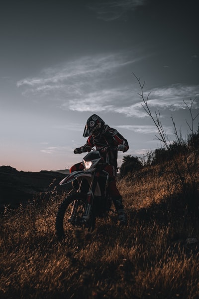 一名身穿黑色和红色摩托车套装的男子在比赛中骑着摩托车在棕色草地上越野